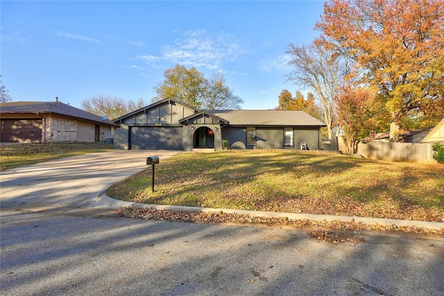 view of front of property with a garage, concrete driveway, a front yard, and fence