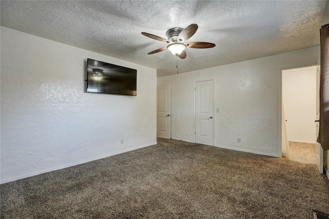 empty room featuring baseboards, ceiling fan, carpet flooring, a textured wall, and a textured ceiling