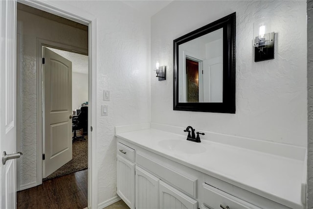 bathroom featuring vanity, wood finished floors, and a textured wall