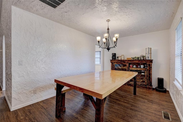 dining space with dark wood-style floors, visible vents, and a textured wall