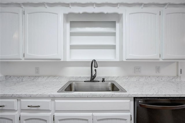 kitchen featuring dishwashing machine, white cabinetry, and a sink