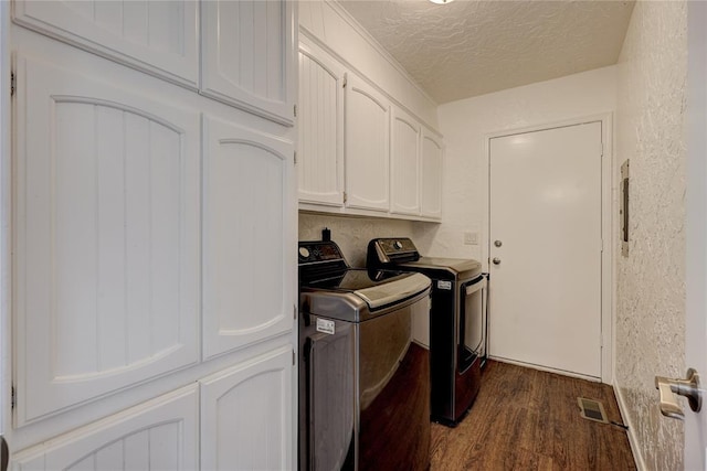 laundry area featuring washer and dryer, cabinet space, a textured ceiling, and a textured wall