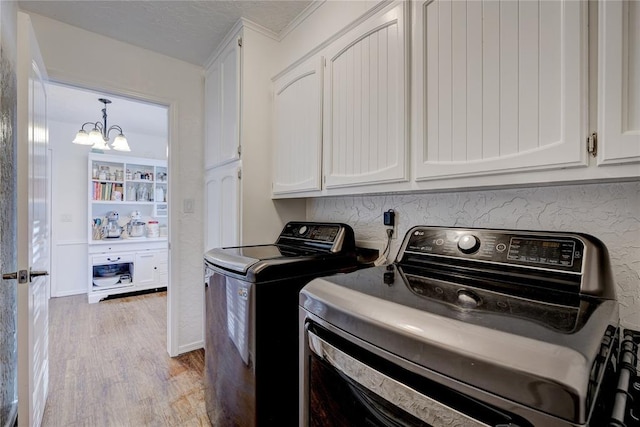 laundry area with a textured ceiling, wood finished floors, washing machine and dryer, cabinet space, and an inviting chandelier