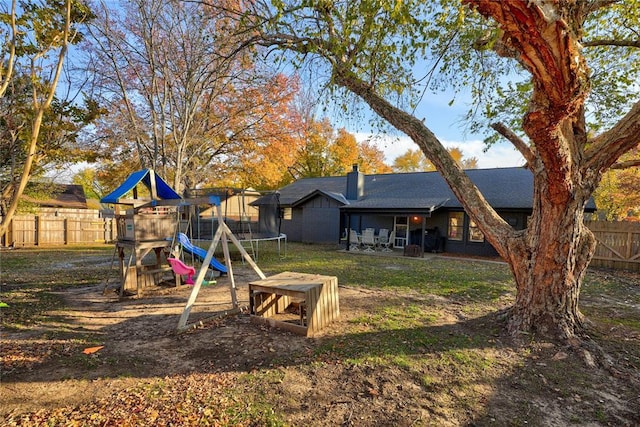 view of yard featuring fence, a trampoline, and a playground