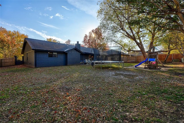 view of yard with a trampoline, a fenced backyard, and a playground