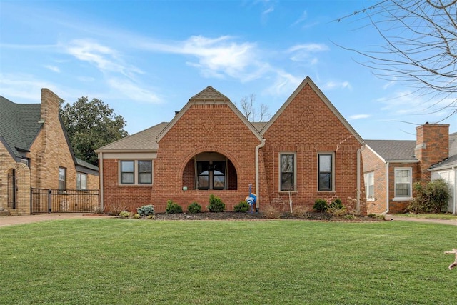 tudor-style house with brick siding and a front lawn