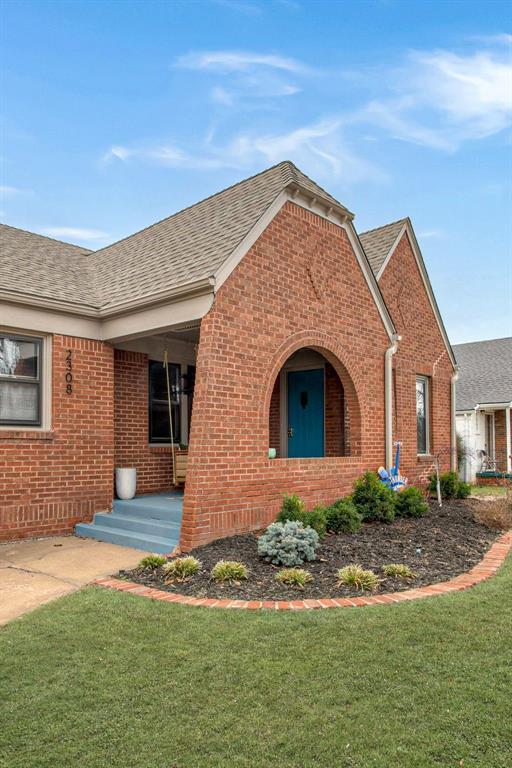 exterior space with a front yard, brick siding, and roof with shingles