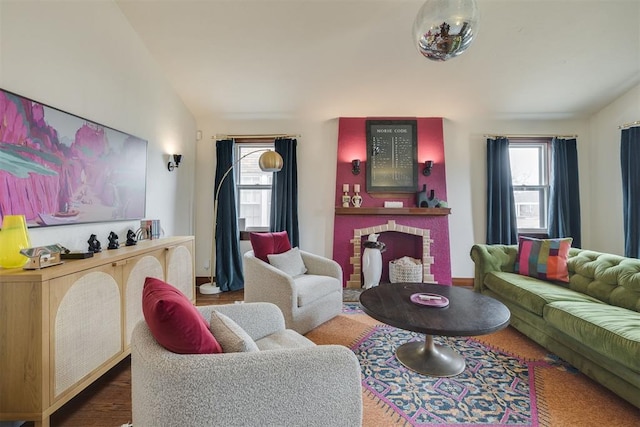 living room featuring lofted ceiling, a brick fireplace, and wood finished floors