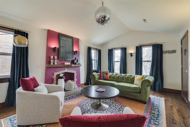 living room featuring a brick fireplace, wood finished floors, baseboards, and vaulted ceiling