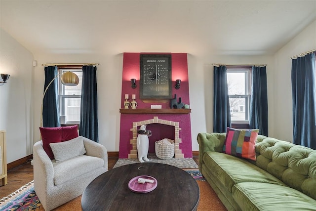 living area with vaulted ceiling, a brick fireplace, wood finished floors, and baseboards