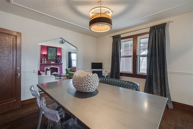 dining room with baseboards, arched walkways, and dark wood-style flooring