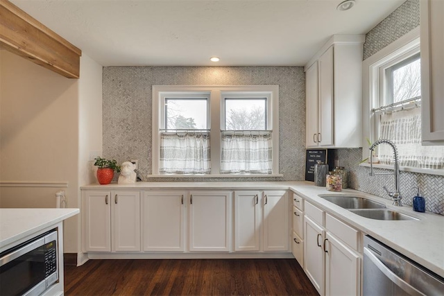 kitchen featuring a sink, stainless steel appliances, backsplash, and white cabinetry