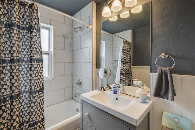 bathroom with a wainscoted wall, shower / bath combination with curtain, and vanity