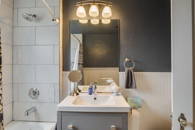 bathroom featuring a wainscoted wall, vanity, and shower / tub combo