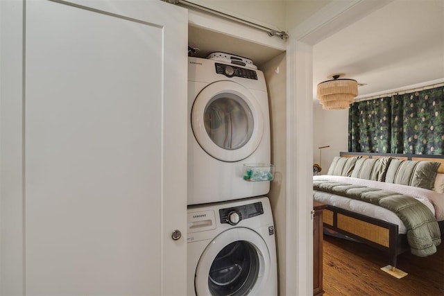 laundry room featuring stacked washer and clothes dryer and wood finished floors