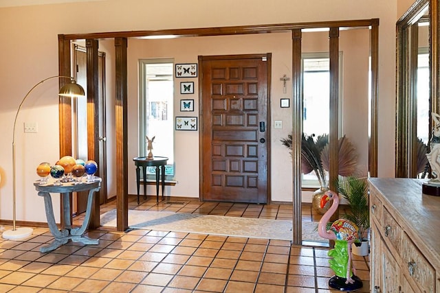 foyer entrance with light tile patterned floors and baseboards