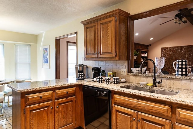 kitchen featuring light stone counters, a peninsula, light tile patterned flooring, a sink, and black dishwasher