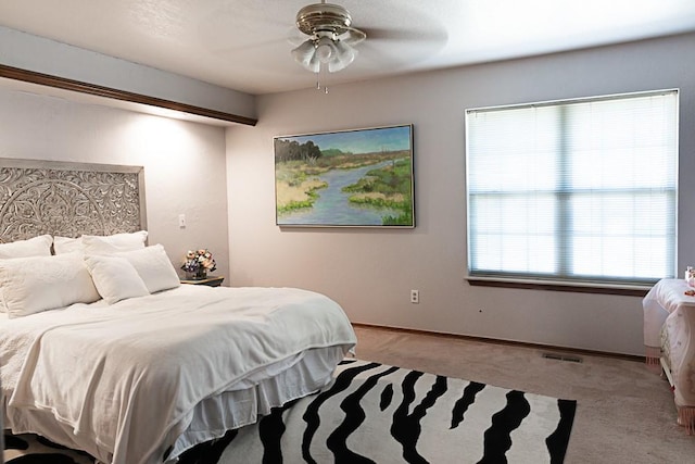 bedroom with visible vents, baseboards, light colored carpet, and a ceiling fan