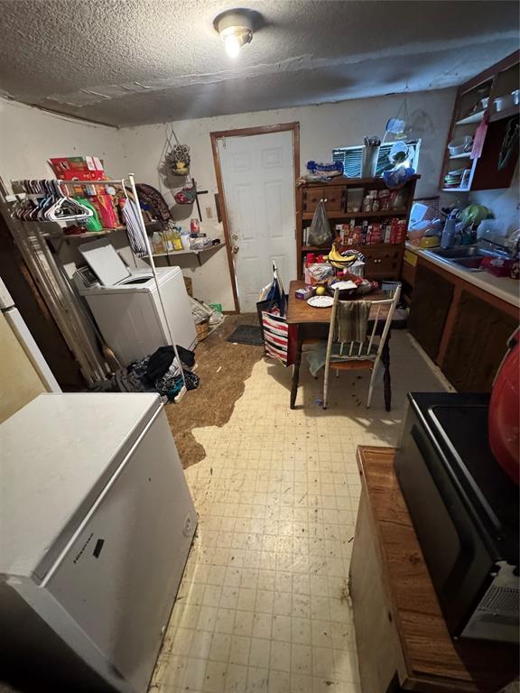 interior space featuring light floors, separate washer and dryer, a sink, stove, and a textured ceiling