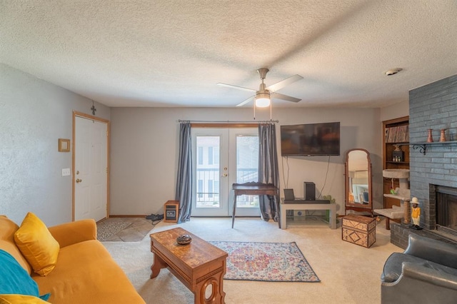 carpeted living room with a textured ceiling, a brick fireplace, french doors, and ceiling fan