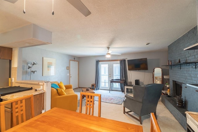 dining area featuring a ceiling fan, a textured ceiling, a fireplace, and light carpet