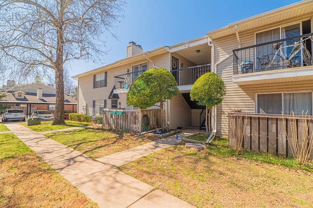 back of property with a yard, a balcony, and a chimney