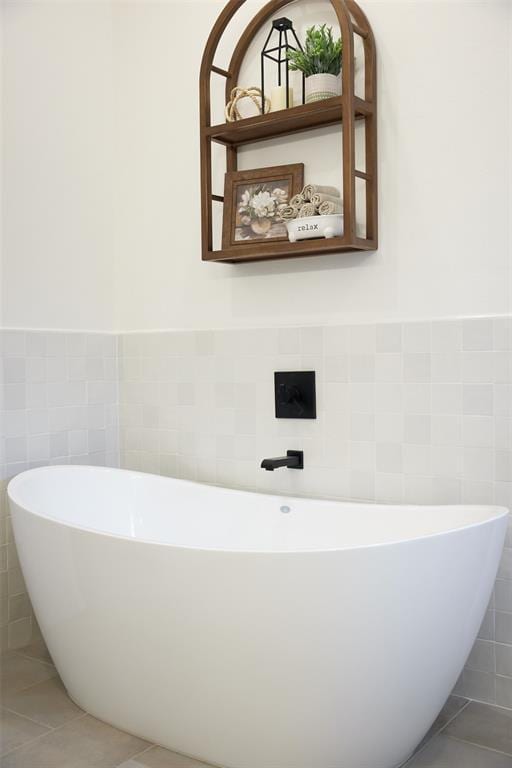 full bath with tile patterned flooring, wainscoting, a freestanding bath, and tile walls