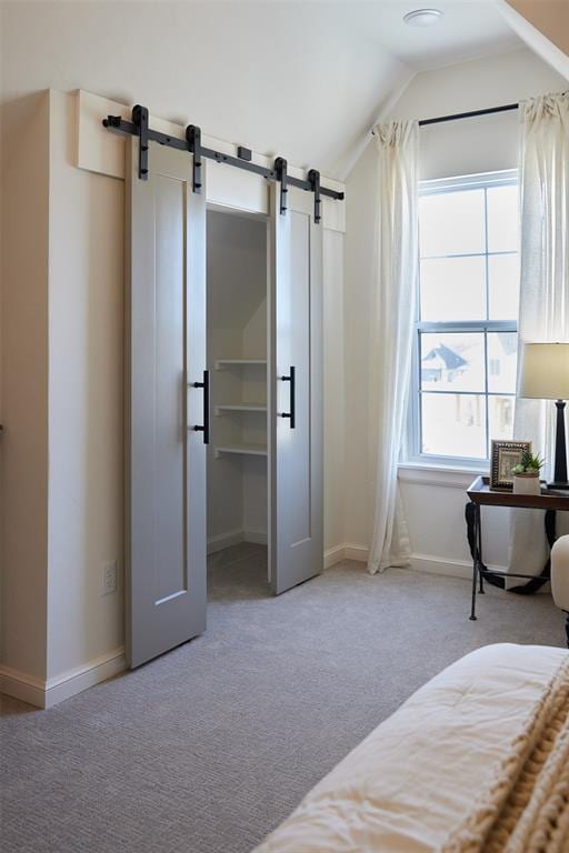 bedroom with carpet flooring, baseboards, a barn door, and vaulted ceiling