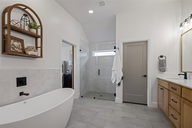 full bathroom with visible vents, tile walls, a shower stall, a soaking tub, and vanity