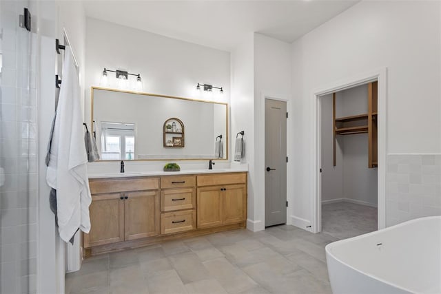 full bath with a sink, a walk in closet, a soaking tub, and double vanity