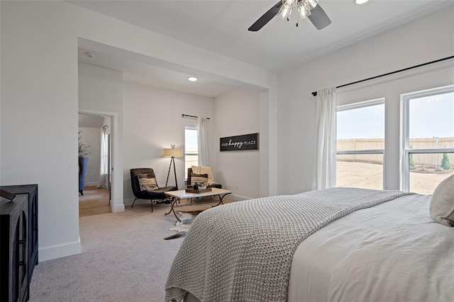 carpeted bedroom featuring baseboards, multiple windows, and a ceiling fan