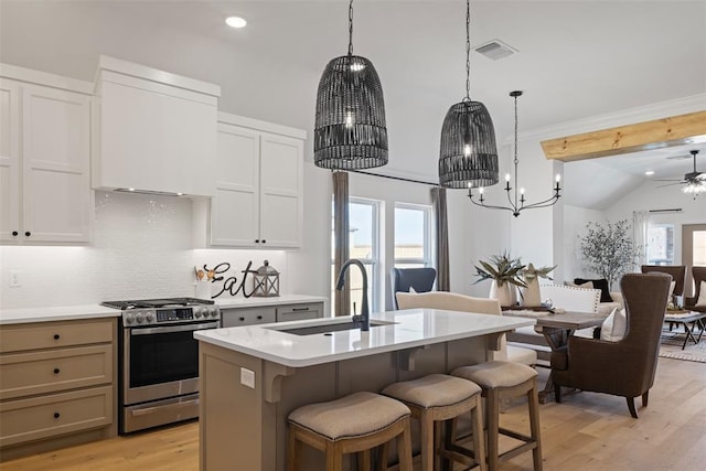 kitchen with light wood-style flooring, decorative backsplash, light countertops, stainless steel gas stove, and open floor plan