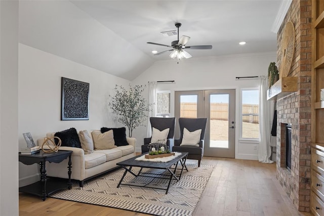 living room featuring visible vents, crown molding, ceiling fan, a fireplace, and light wood-style floors