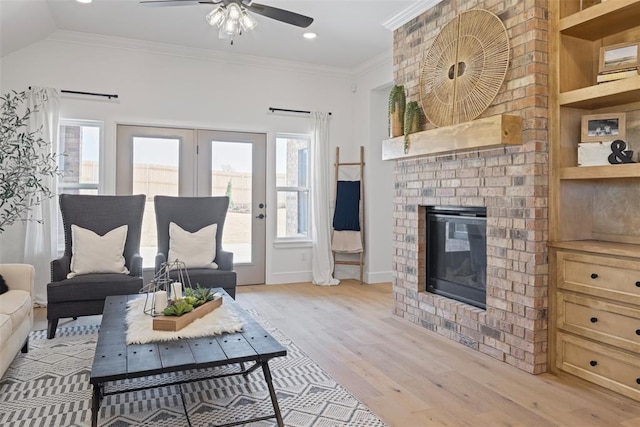 living area with ceiling fan, a brick fireplace, plenty of natural light, and ornamental molding