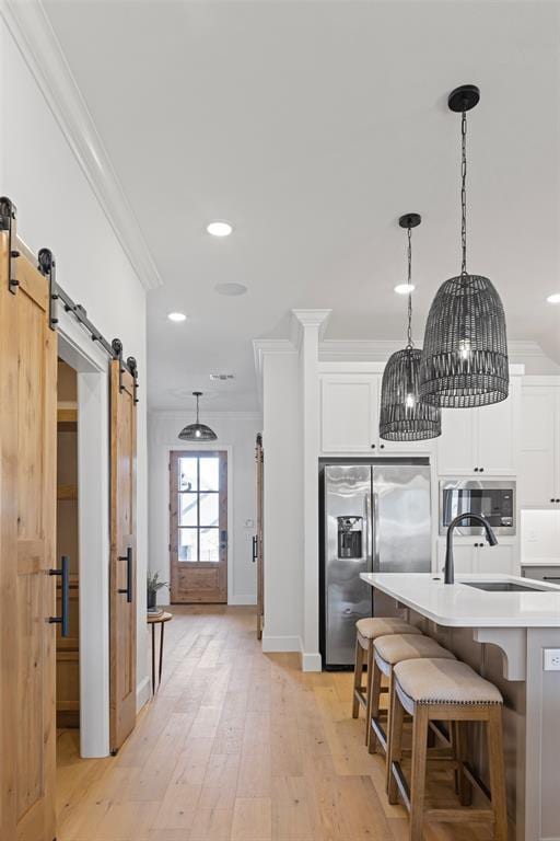 kitchen with stainless steel appliances, a barn door, and crown molding