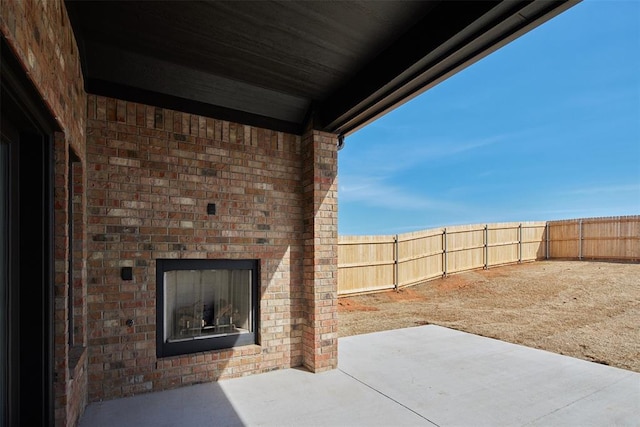 view of patio / terrace featuring a fenced backyard and an outdoor brick fireplace