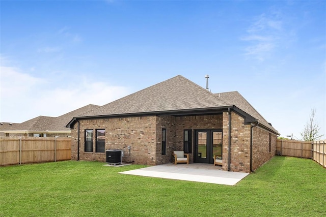 rear view of house featuring a yard, a patio, brick siding, and central AC unit