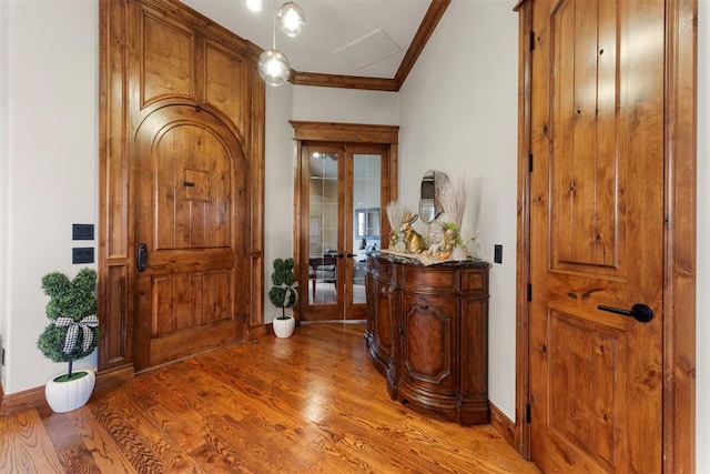 foyer featuring wood finished floors, baseboards, french doors, and ornamental molding