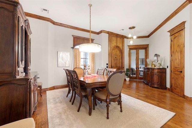 dining space with visible vents, french doors, light wood-style floors, crown molding, and baseboards