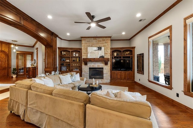 living area featuring baseboards, ornamental molding, a stone fireplace, recessed lighting, and dark wood-style floors