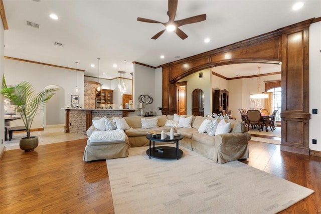 living area with a ceiling fan, wood finished floors, visible vents, recessed lighting, and arched walkways