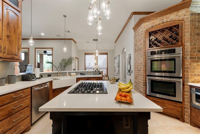 kitchen featuring a sink, a center island, stainless steel appliances, brown cabinetry, and crown molding