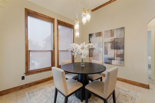 dining room with light tile patterned floors, baseboards, arched walkways, and an inviting chandelier