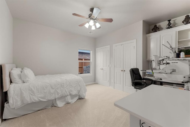 bedroom with multiple closets, light carpet, and ceiling fan