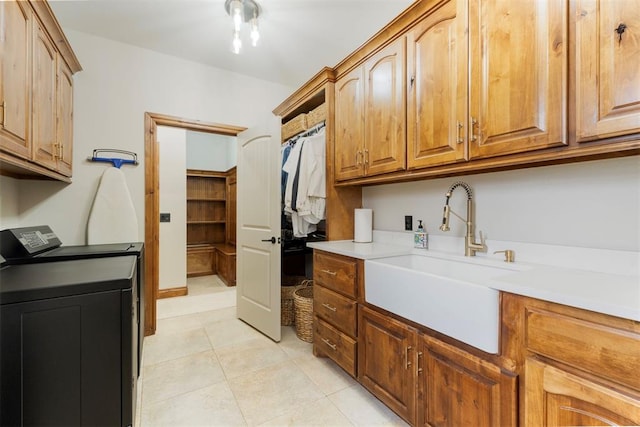 laundry room featuring washer and clothes dryer, light tile patterned floors, cabinet space, and a sink