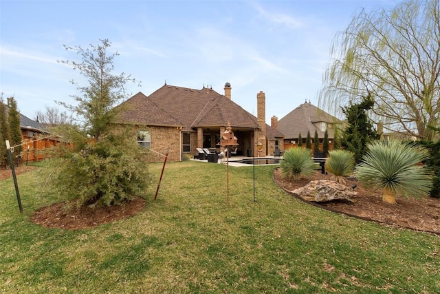 back of house featuring a patio area, a lawn, brick siding, and fence