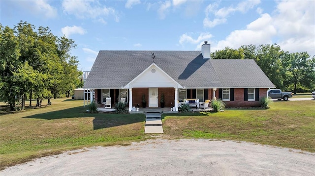 view of front facade with a front lawn, a porch, brick siding, and a chimney