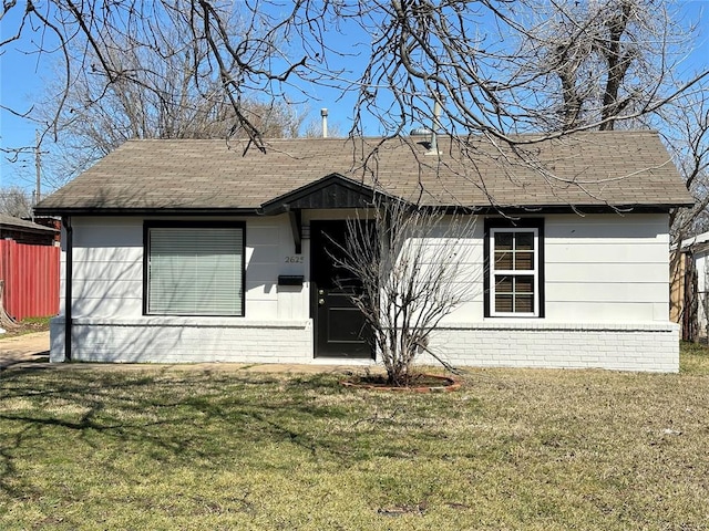 single story home with brick siding, a front lawn, and roof with shingles