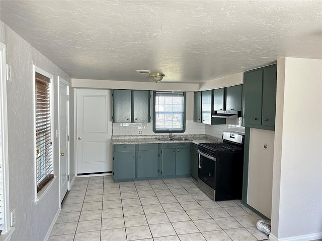 kitchen featuring tasteful backsplash, stainless steel gas range, a textured wall, and a sink