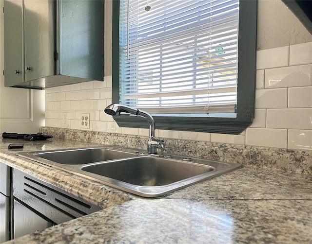 kitchen with decorative backsplash, light countertops, and a sink